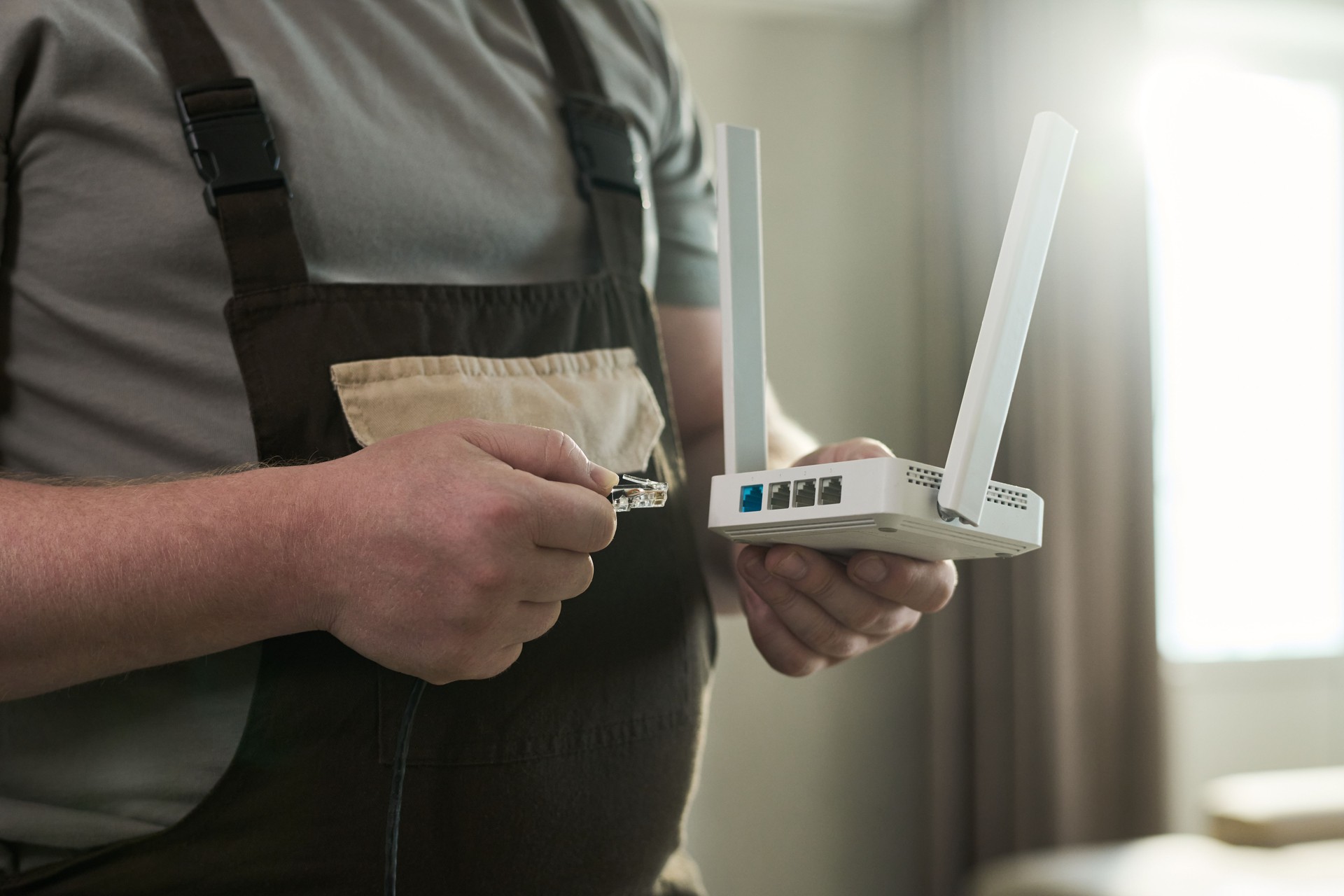 Middle Aged Caucasian Man Connecting Ethernet Cable to Wireless Router Device