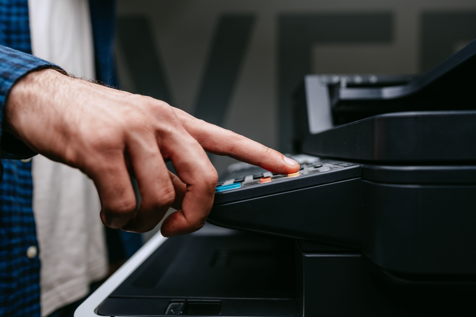 Person uses a multifunction printer to operate photocopying or scanning functions in an office setting during daylight hours